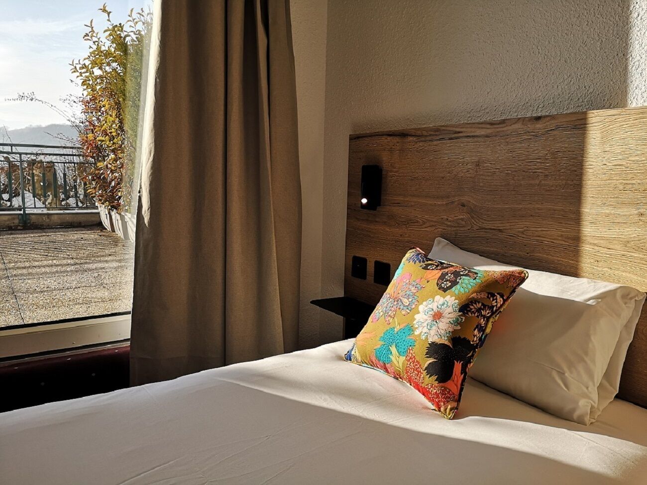 Una camera d'hotel con un letto, una finestra con tende e vista su un edificio.