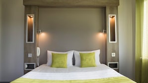 Habitación de hotel con una cama grande, dos mesitas de noche, un teléfono e iluminación en la pared.
