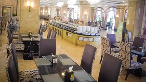 Un hall d’hôtel doté d’un espace buffet central, de plusieurs coins salon et d’un lustre.
