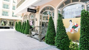 Un bâtiment avec une enseigne indiquant un service de massage, un escalier et des haies soigneusement taillées.
