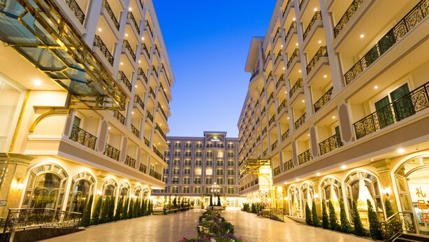 Un atrium d’hôtel s’étendant sur plusieurs étages, avec un escalier central et un grand bac à fleurs décoratif.
