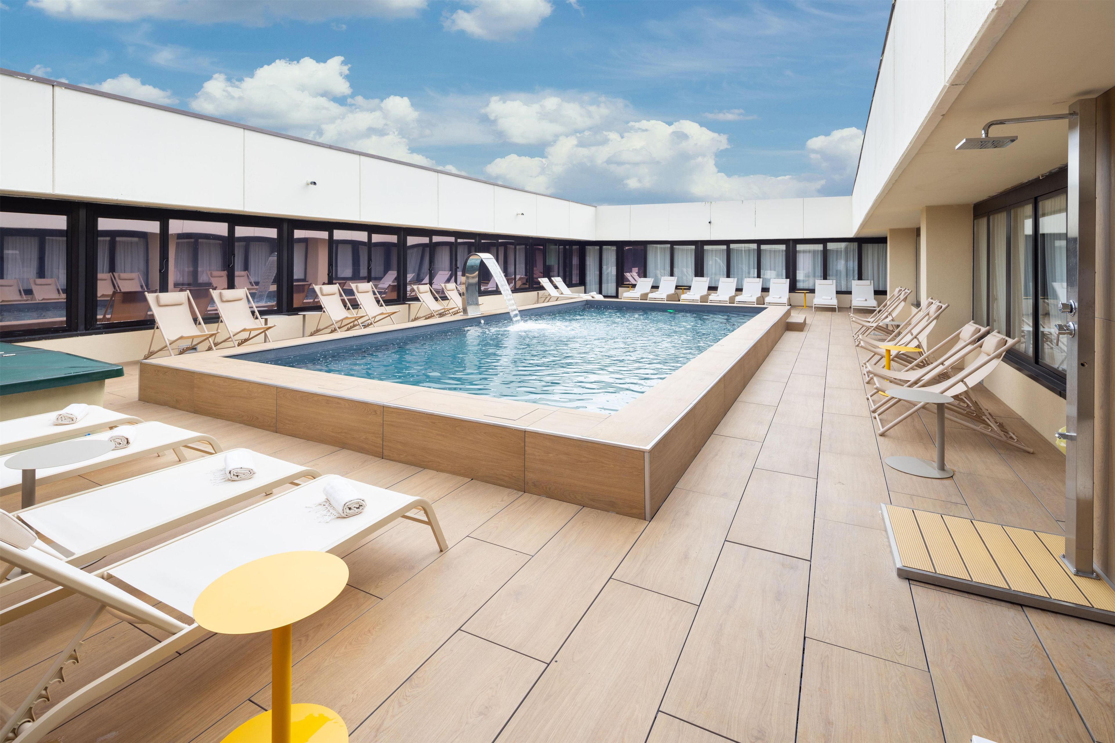 A rooftop pool area with lounge chairs and a swimming pool.