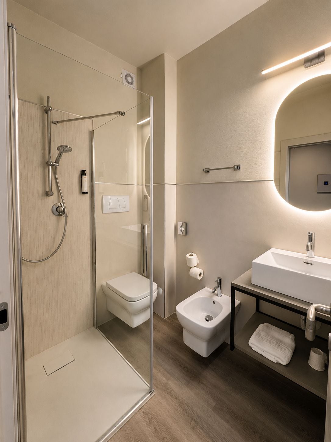 Ein modernes Badezimmer mit einer Duschkabine, einer Toilette, einem Bidet und einem Waschbecken mit Spiegel.