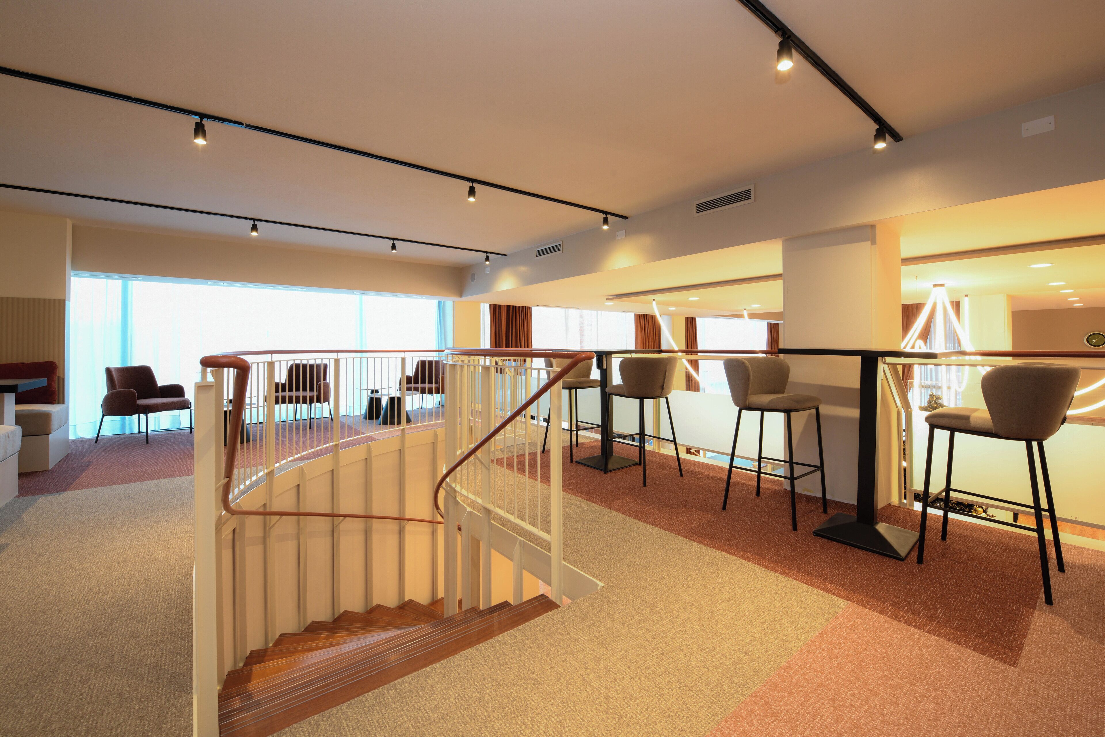 Ein modernes Interieur mit Treppe, Sitzgelegenheit und großen Fenstern.