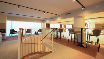 Ein modernes Interieur mit Treppe, Sitzgelegenheit und großen Fenstern.
