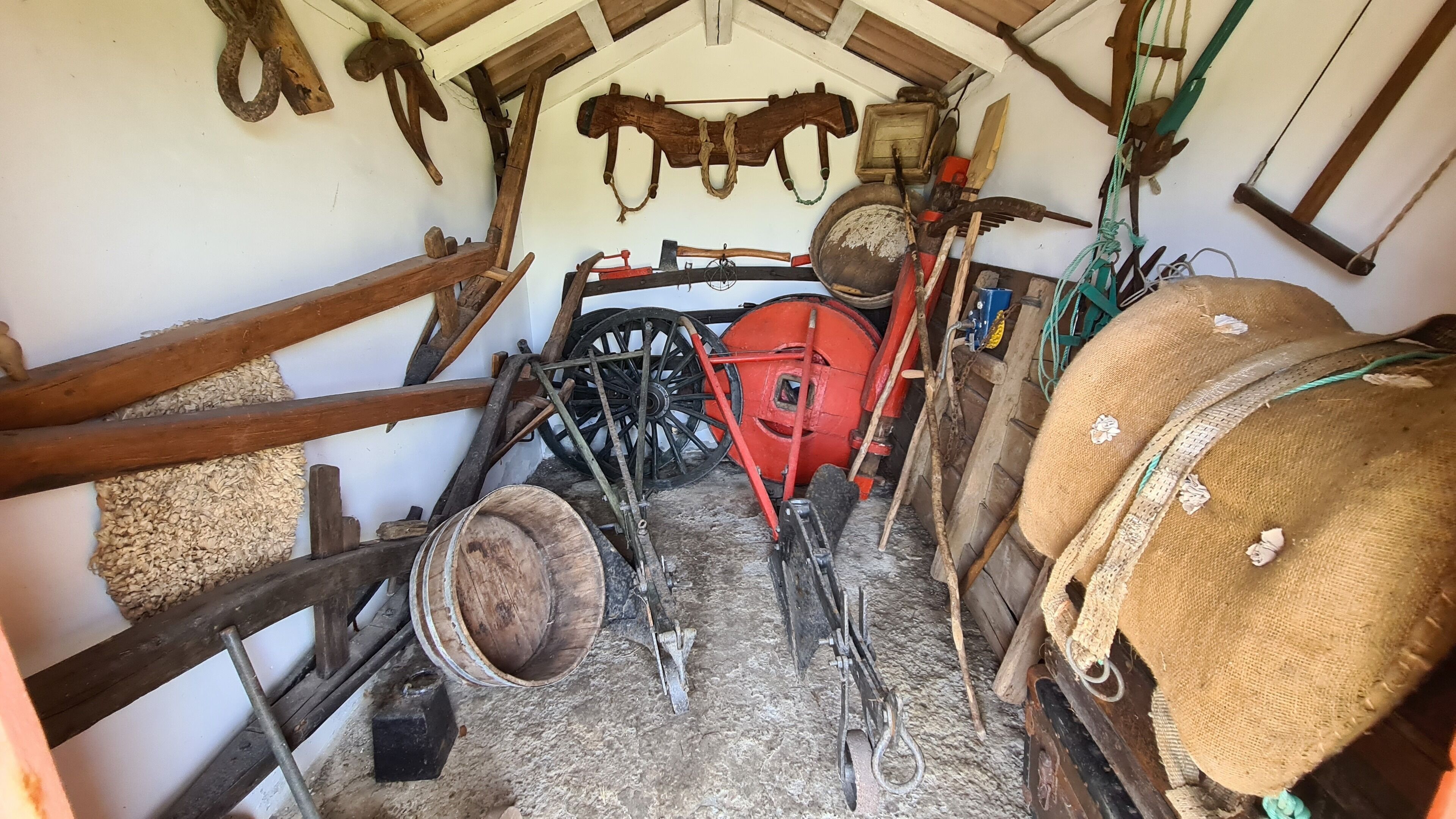 A rustic room with wooden beams, a red mechanical device, and various tools hanging on the walls.