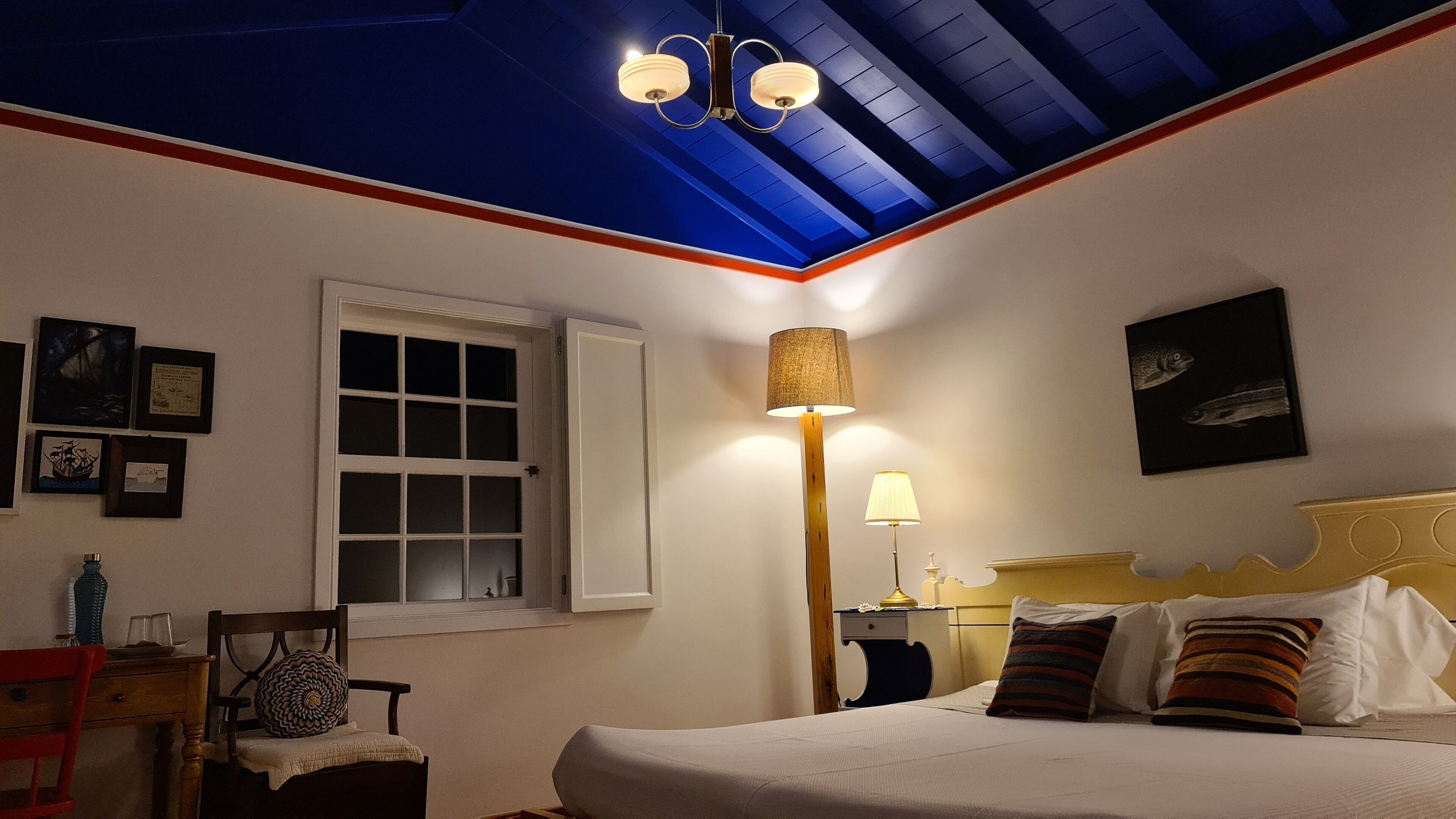 Un dormitorio con cama, ventana, lámpara y luz en el techo.