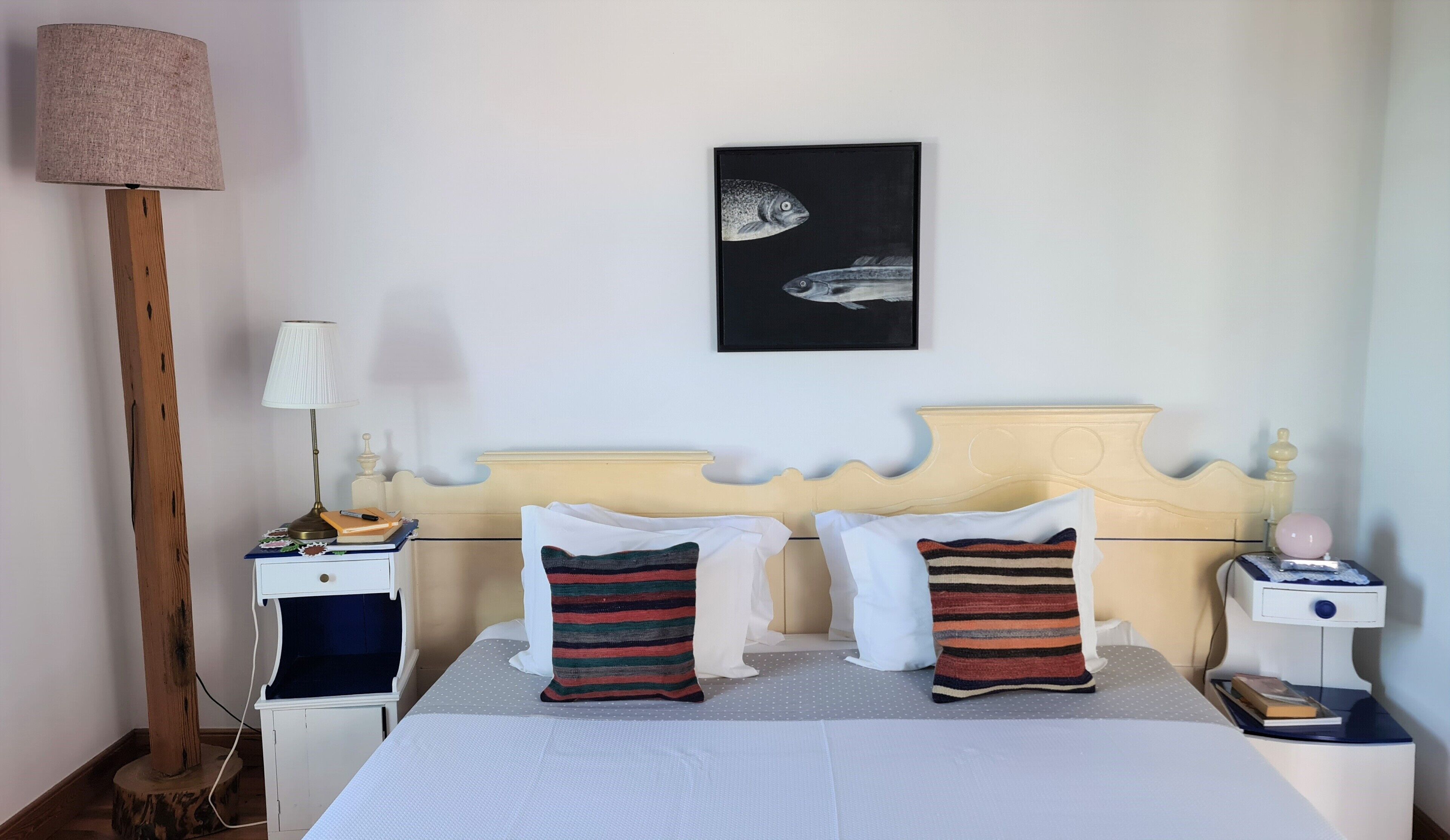 A neatly arranged bedroom with a bed, two bedside tables, a lamp, and a framed picture on the wall.