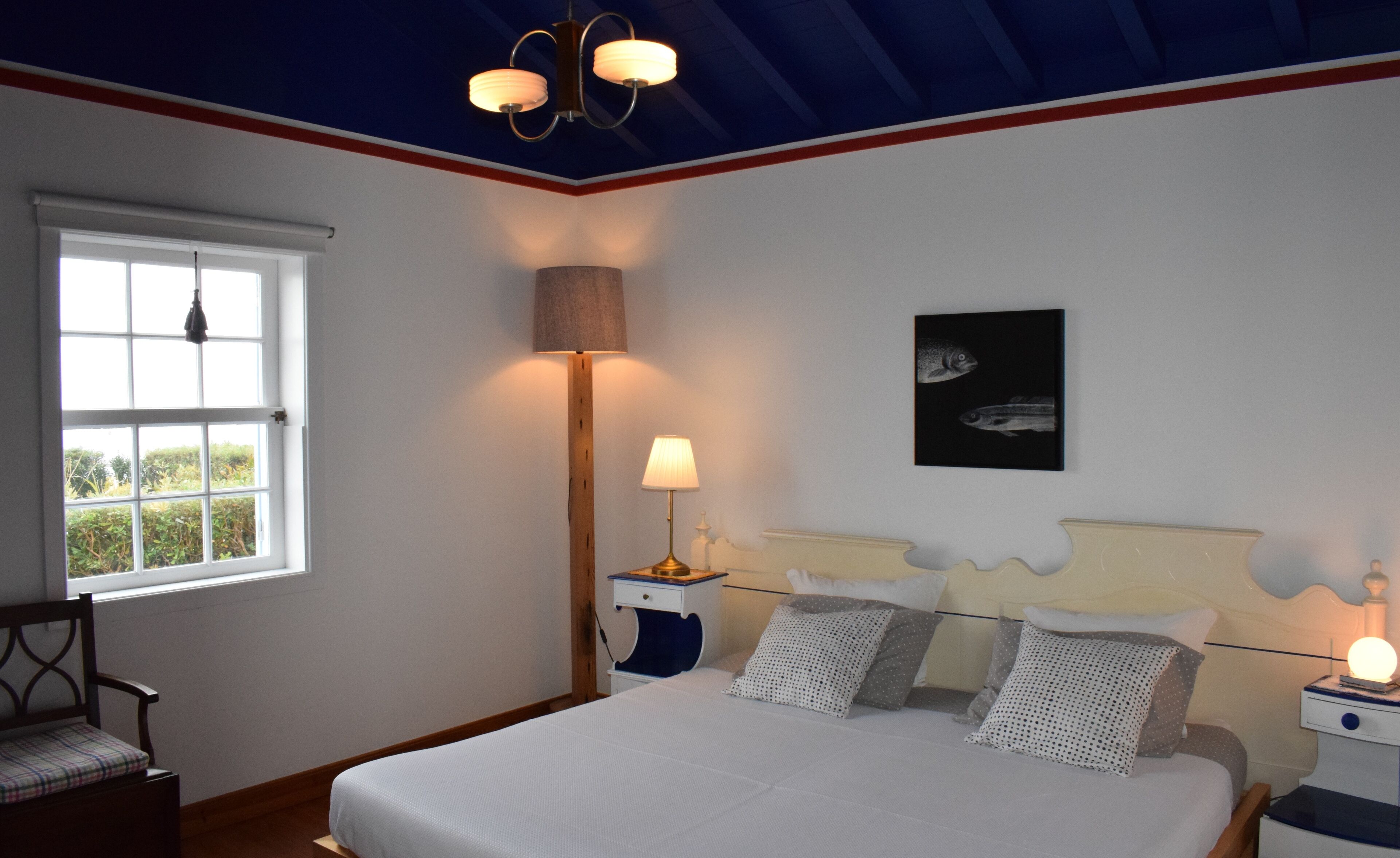 Ein Schlafzimmer mit einem Bett, Nachttischen, einer Lampe, einem Sessel und einem Fenster.