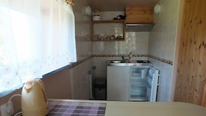 A compact kitchen with a refrigerator, a kettle, and a small countertop. - Villa Zveju 29 (Palanga)