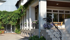 A building with a covered porch, stone steps, and potted plants. - Villa Zveju 29 (Palanga)