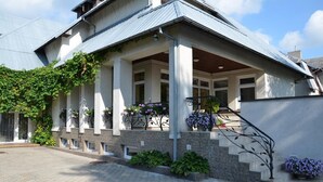 A two-story house with a covered porch, stone steps, and a metal staircase. - Villa Zveju 29 (Palanga)