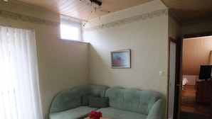 A living room with a green sofa, a wooden coffee table, and a painting on the wall. - Villa Zveju 29 (Palanga)