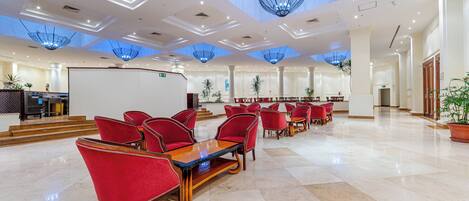 A spacious lobby with red chairs, a reception desk, and a large whiteboard.