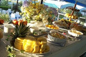 A buffet table with various fruits, vegetables, and a flower arrangement. - Monaco Quisisana (Jesolo)
