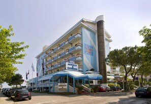 A hotel with a blue and white facade, multiple balconies, and a sign indicating it is the Monaco & Qvisisana hotel. - Monaco Quisisana (Jesolo)