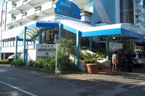 A hotel entrance with a blue canopy, a sign reading 'Monaco & Quisiana,' and a no parking sign. - Monaco Quisisana (Jesolo)