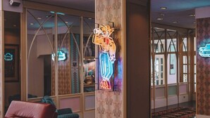 A modern lobby with a neon tiger decoration, leather seating, and a reflective floor. - Monaco Quisisana (Jesolo)