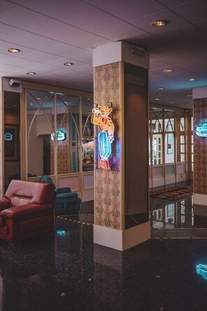 A modern lobby with a neon tiger decoration, leather seating, and a reflective floor. - Monaco Quisisana (Jesolo)