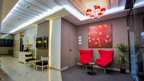A modern reception area with a desk, chairs, a clock, and a red artwork on the wall. - Ravvda Hotel Bakırköy (Istanbul)