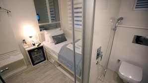 A compact hotel room with a bed, bedside table, and a small cabinet. - Ravvda Hotel Bakırköy (Istanbul)
