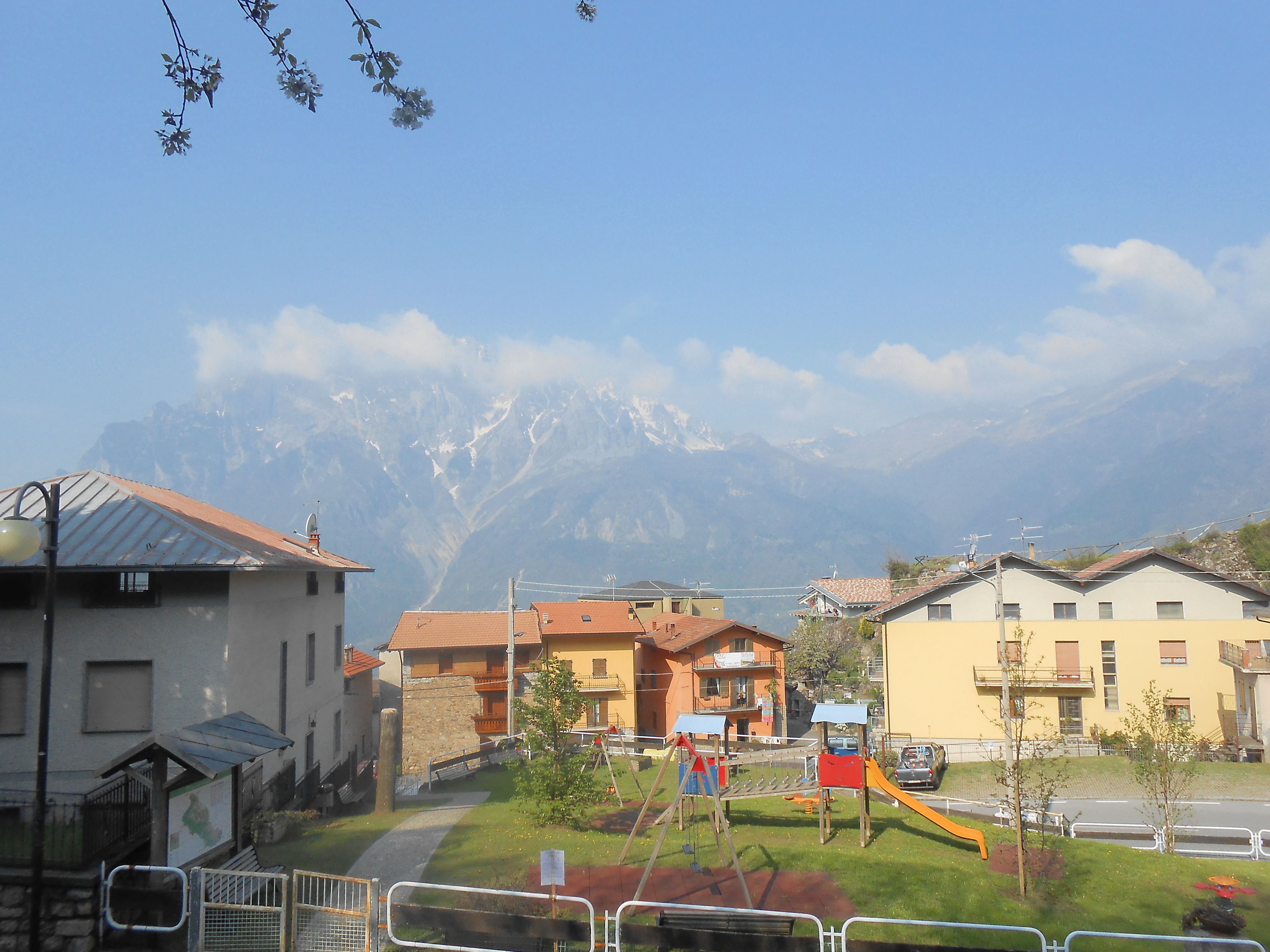 A residential area with houses, a playground, and a mountain backdrop.