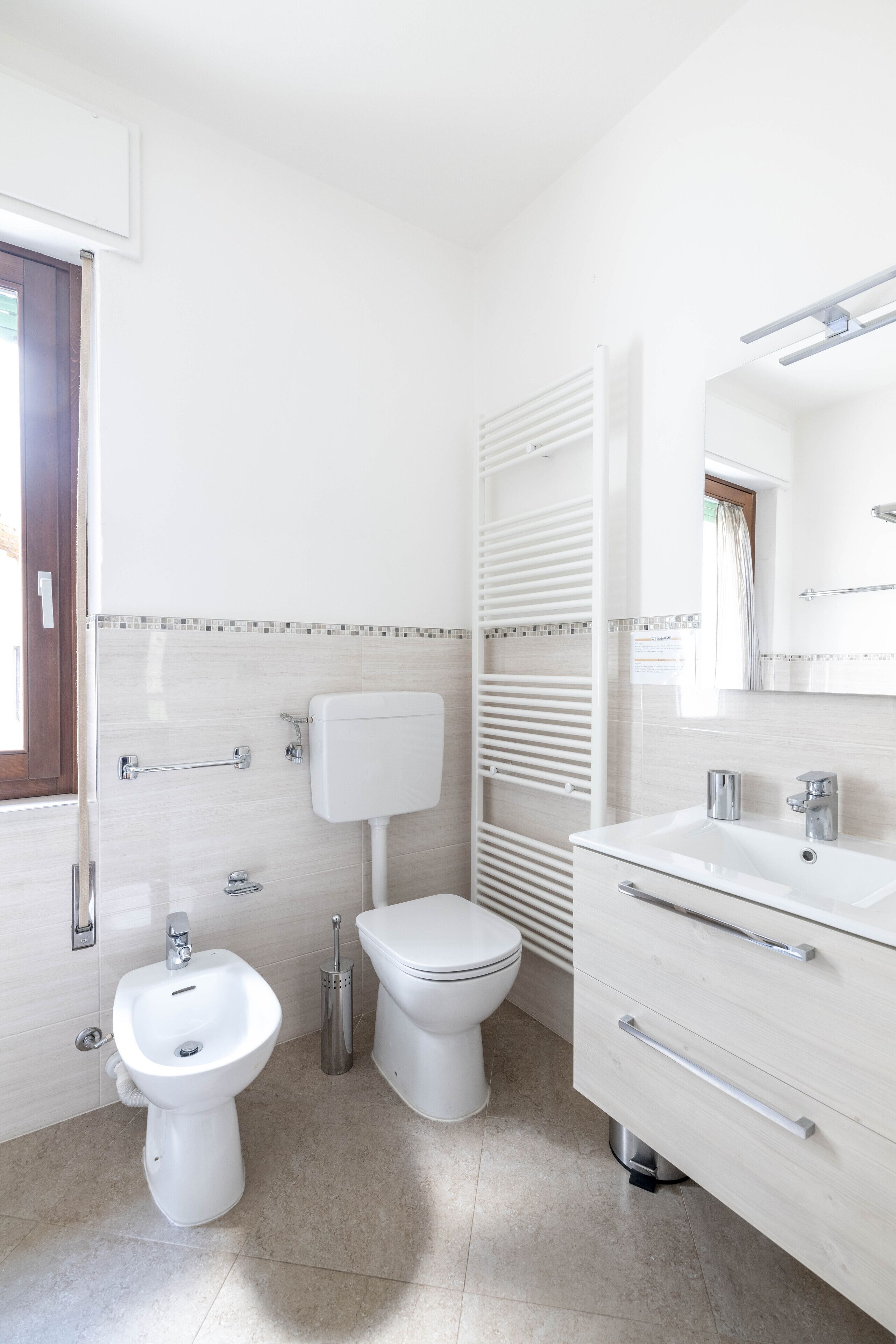 Un bagno moderno con toilette, bidet, lavabo e specchio.