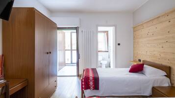 Quarto com duas camas, guarda-roupa de madeira e televisão.