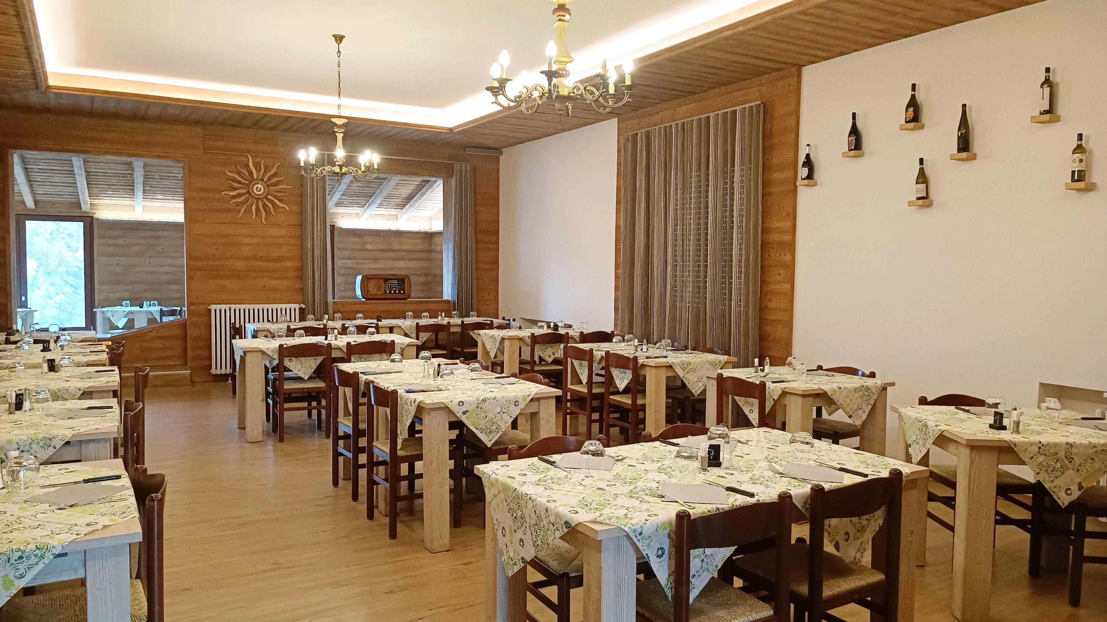 Un ristorante con diversi tavoli, sedie di legno e un lampadario.