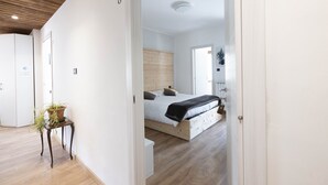 A bedroom with a wooden headboard, a bedside table with a plant, and a bed with a black blanket. - B&B Castello (Cimbergo)