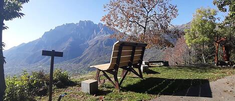 Un banc avec vue sur la montagne, un panneau indicateur et un sentier dallé.