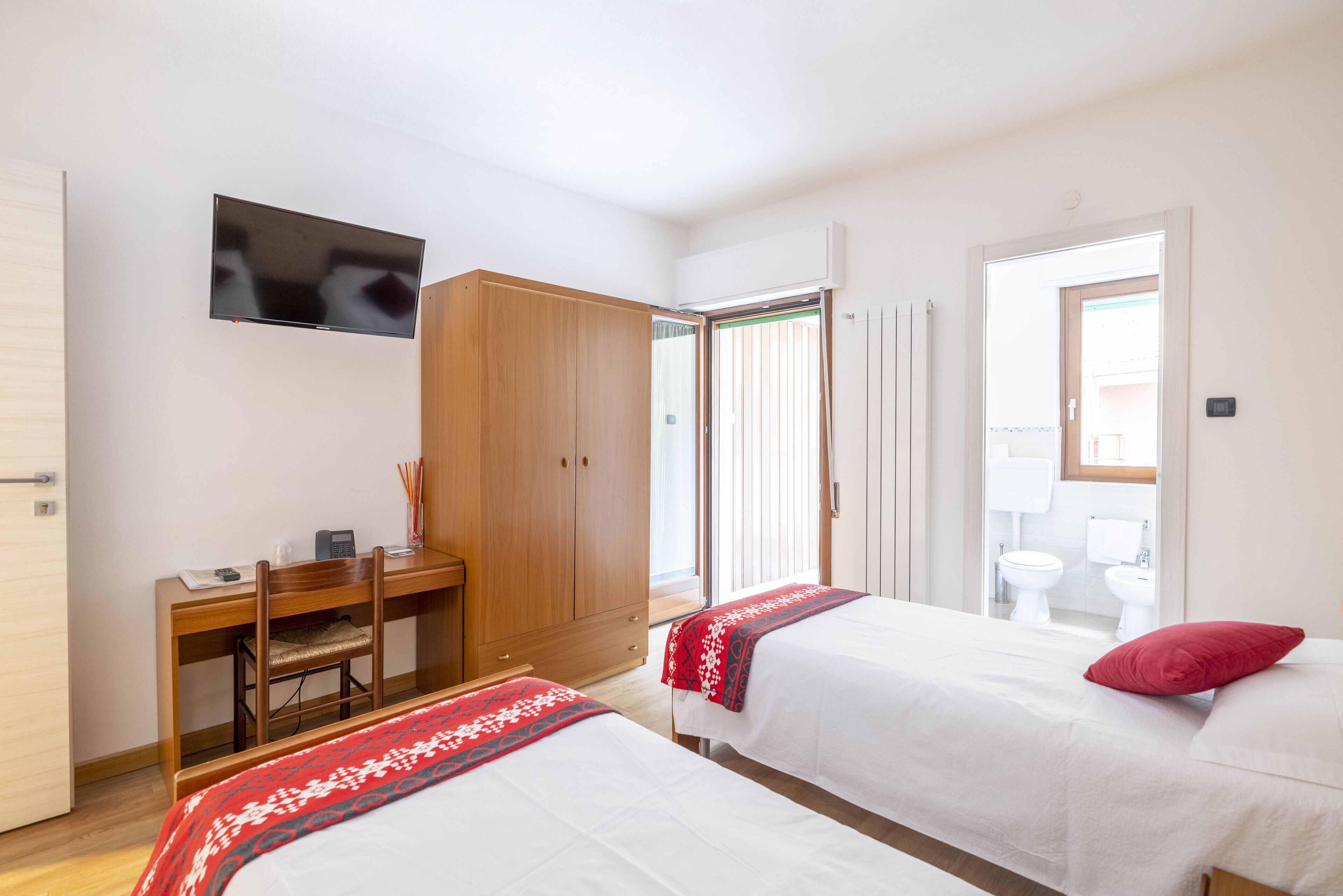 A hotel room with two beds, a desk, a TV, and a wardrobe.