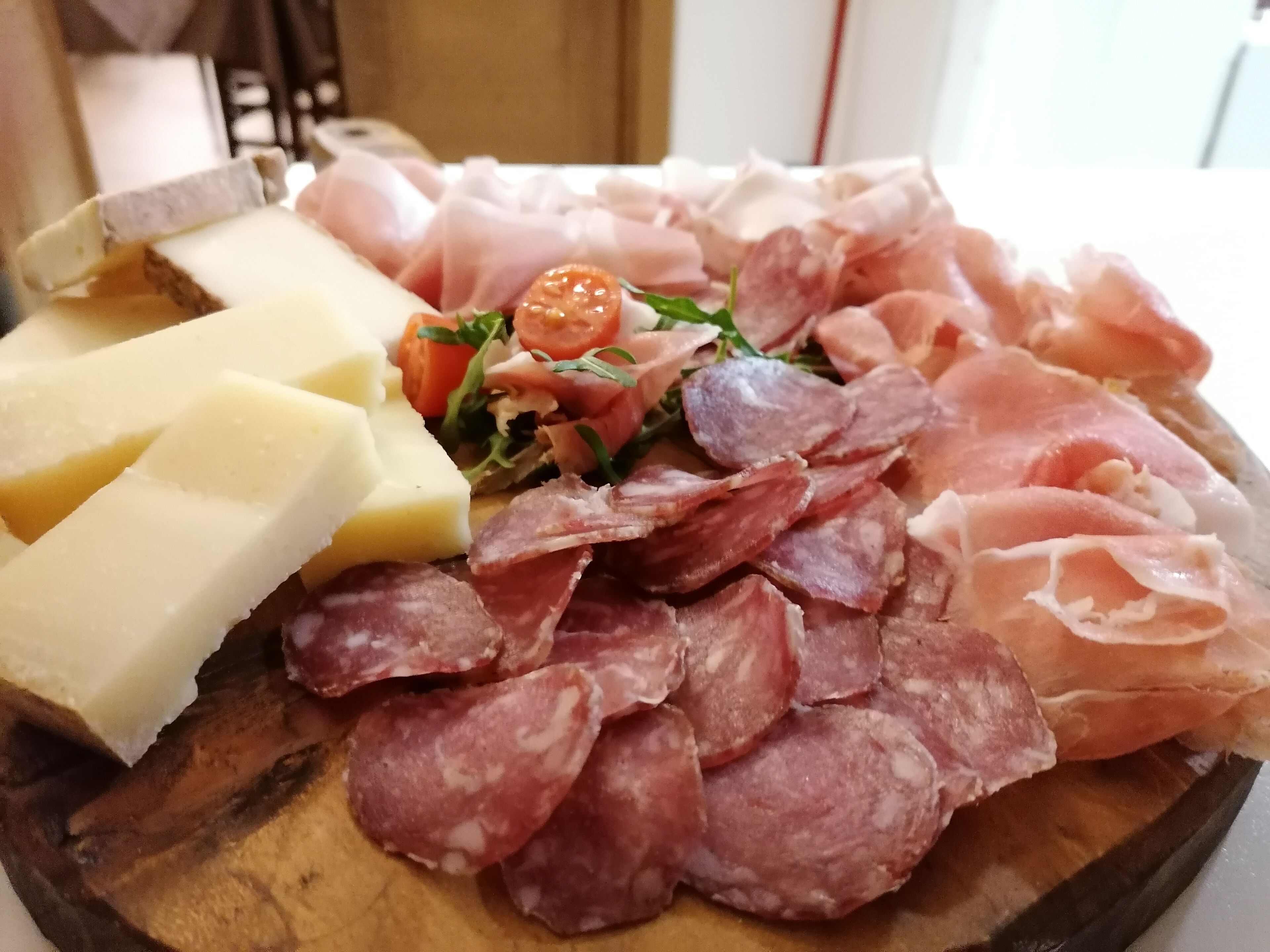 A charcuterie board with various meats, cheeses, and vegetables.