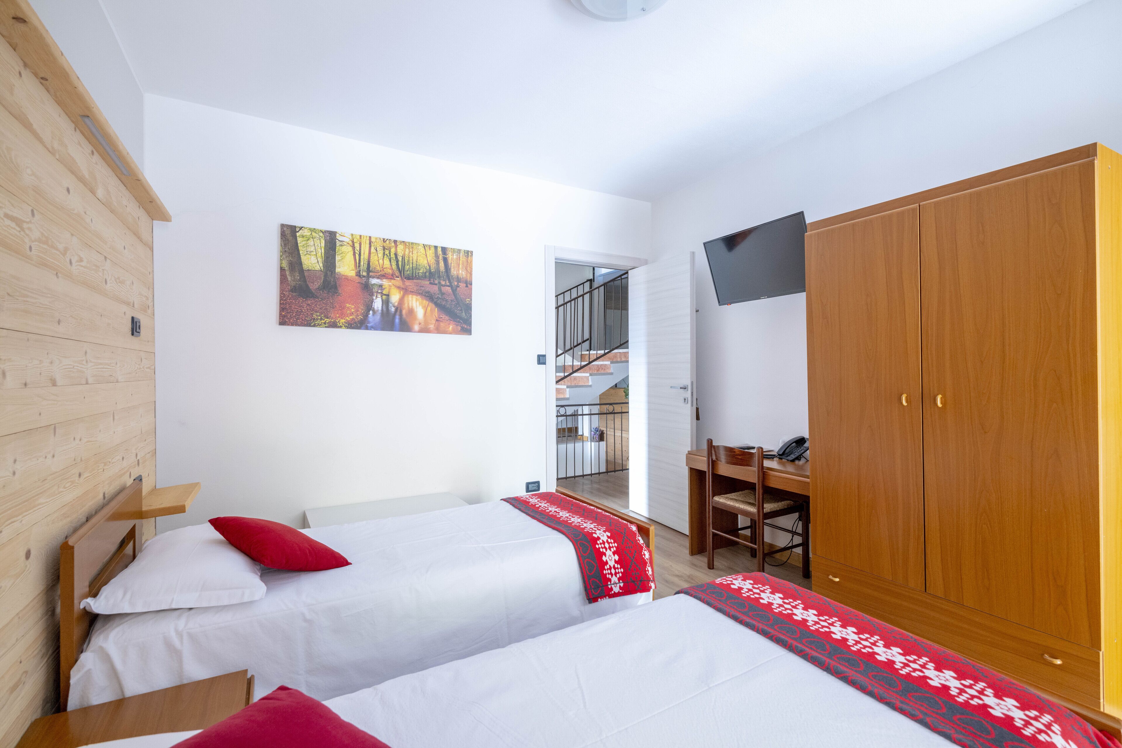 Un dormitorio con dos camas, un armario de madera, un escritorio y un cuadro en la pared.