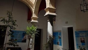 A courtyard with arches, a wooden balcony, and hanging lanterns. - Casa Del Regidor (El Puerto de Santa Maria)