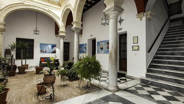 A spacious lobby with a checkered floor, columns, and potted plants. - Casa Del Regidor (El Puerto de Santa Maria)