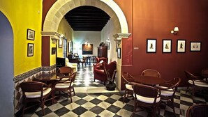 A hotel lobby with checkered flooring, wooden furniture, and framed artwork on the walls. - Casa Del Regidor (El Puerto de Santa Maria)