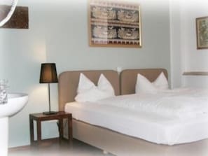 A hotel room with a bed, bedside table, lamp, and a wall-mounted artwork. - CityMinis (Düsseldorf)