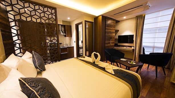 Een hotelkamer met een groot bed, een bureau met stoel, een televisie en een eettafel met stoelen.