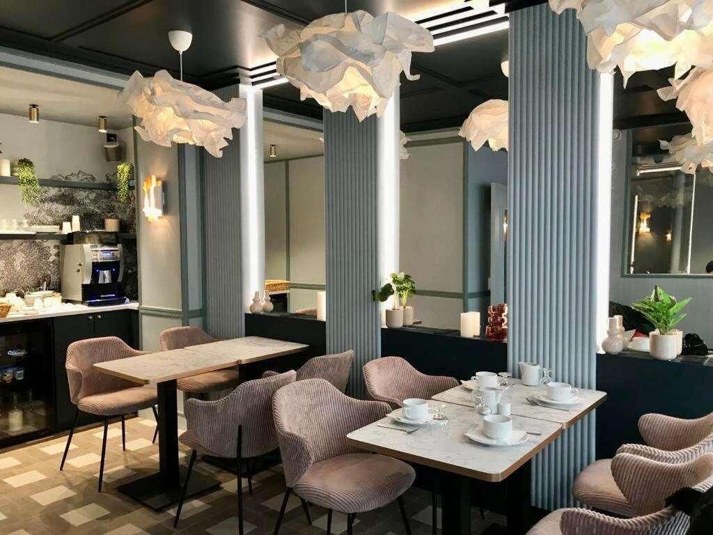 Et moderne spiseområde med et langt bord, stole, kaffemaskine og dekorative planter.