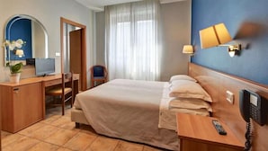 Une chambre d’hôtel équipée d’un lit, d’un bureau, d’une chaise, d’une télévision et d’un téléphone fixé au mur.
