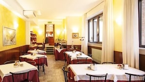 Un restaurant où les tables sont recouvertes de nappes blanches, les murs sont en bois et les œuvres d’art sont exposées dans des cadres.