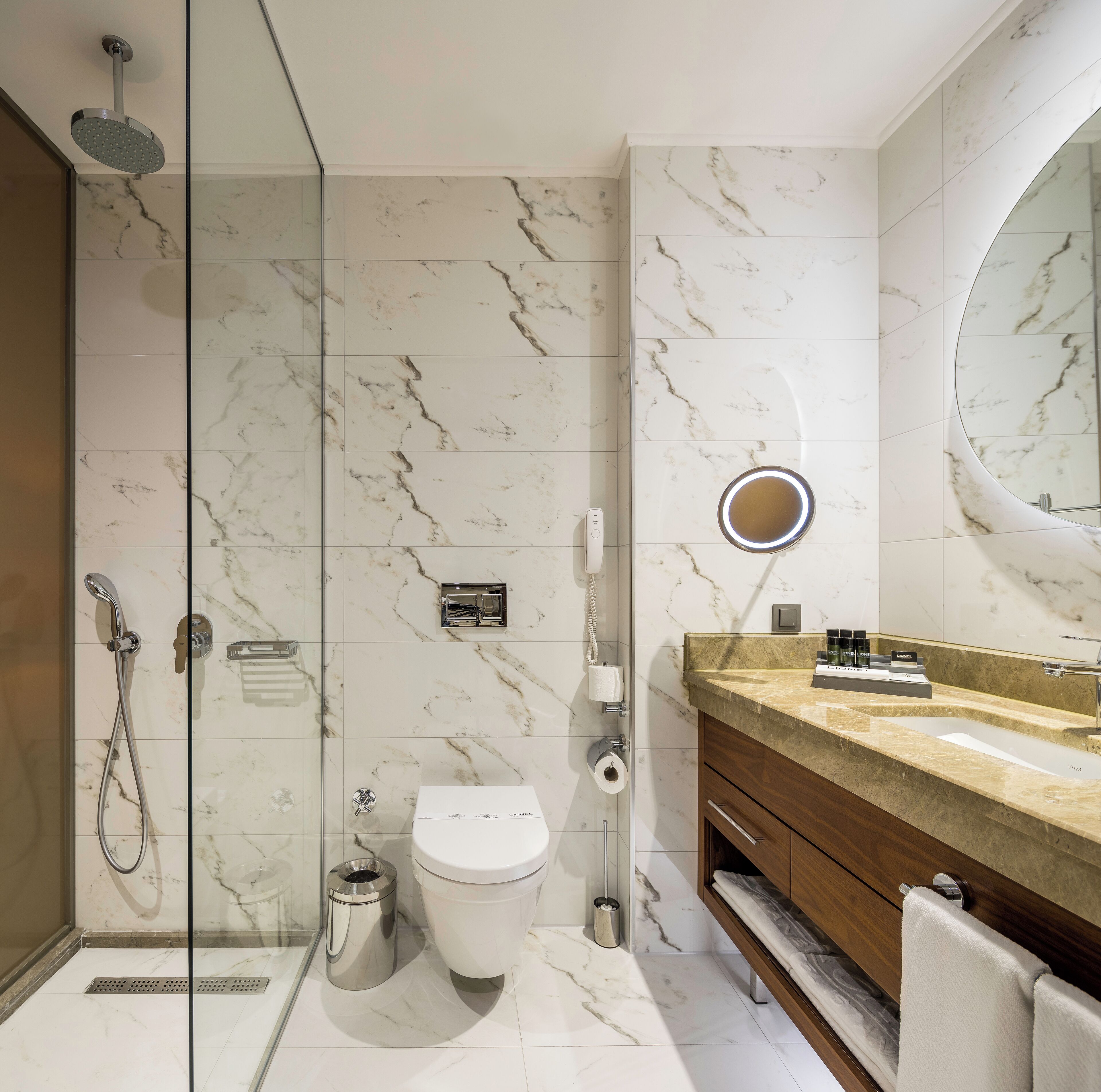 Een moderne badkamer met een douchecabine van glas, een toilet en een wastafel met spiegel.