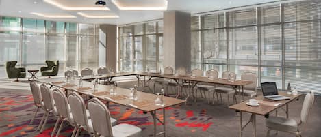 Una sala de conferències amb una taula llarga, diverses cadires i un portàtil sobre una taula.