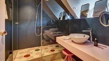 Une salle de bain moderne avec une douche à parois de verre, un grand lavabo blanc et un tabouret rose.