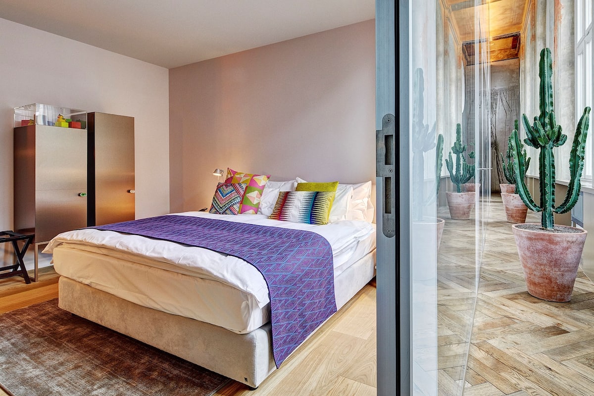 A modern bedroom with a bed, a wardrobe, and a potted cactus plant.