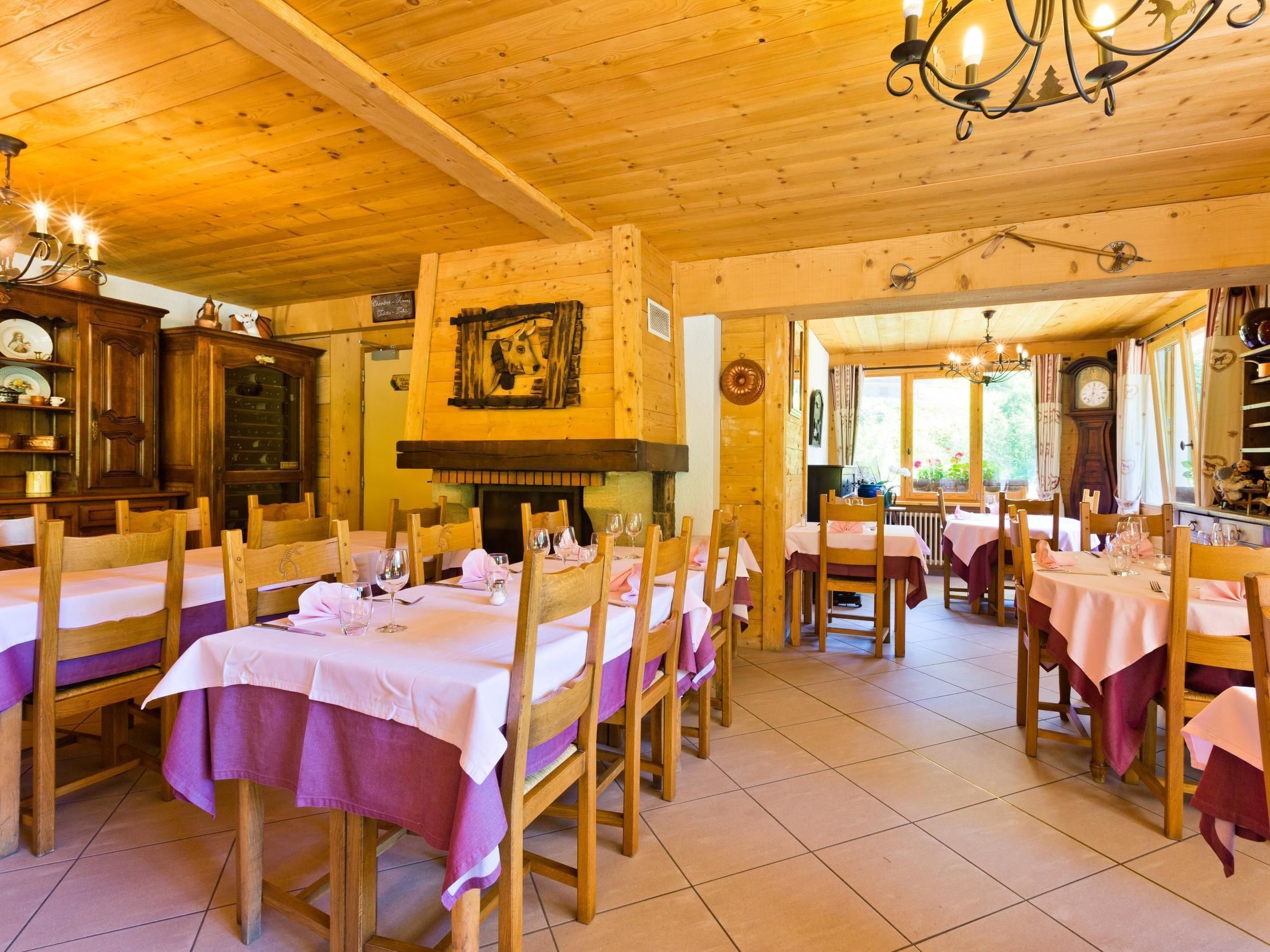 A cozy restaurant with wooden interiors, multiple dining tables, and a fireplace.