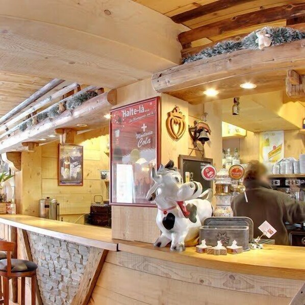 A wooden interior with a counter, a cow statue, and a sign reading "Halte-la...".