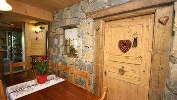 A wooden dining table with chairs, a potted plant, and a stone wall.