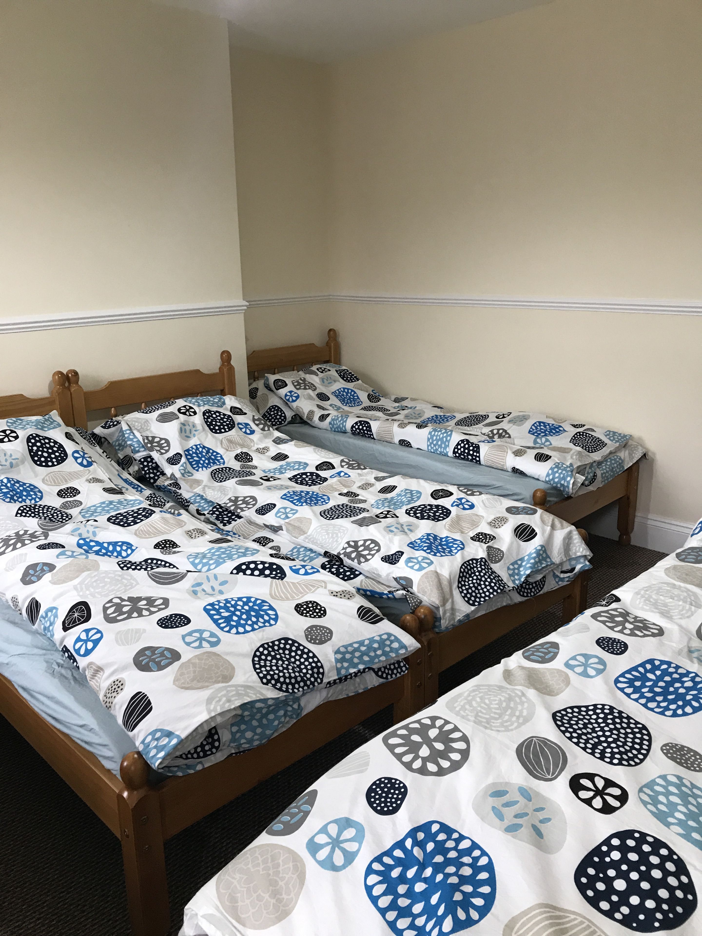 Une chambre avec trois lits en bois, chacun recouvert d’une couverture à motifs.